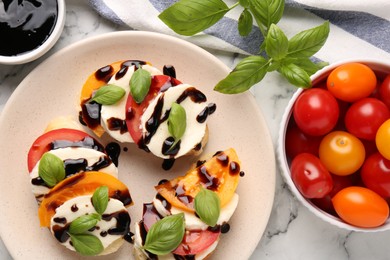 Photo of Delicious bruschettas with mozzarella cheese, tomatoes, balsamic vinegar and ingredients on white table, flat lay
