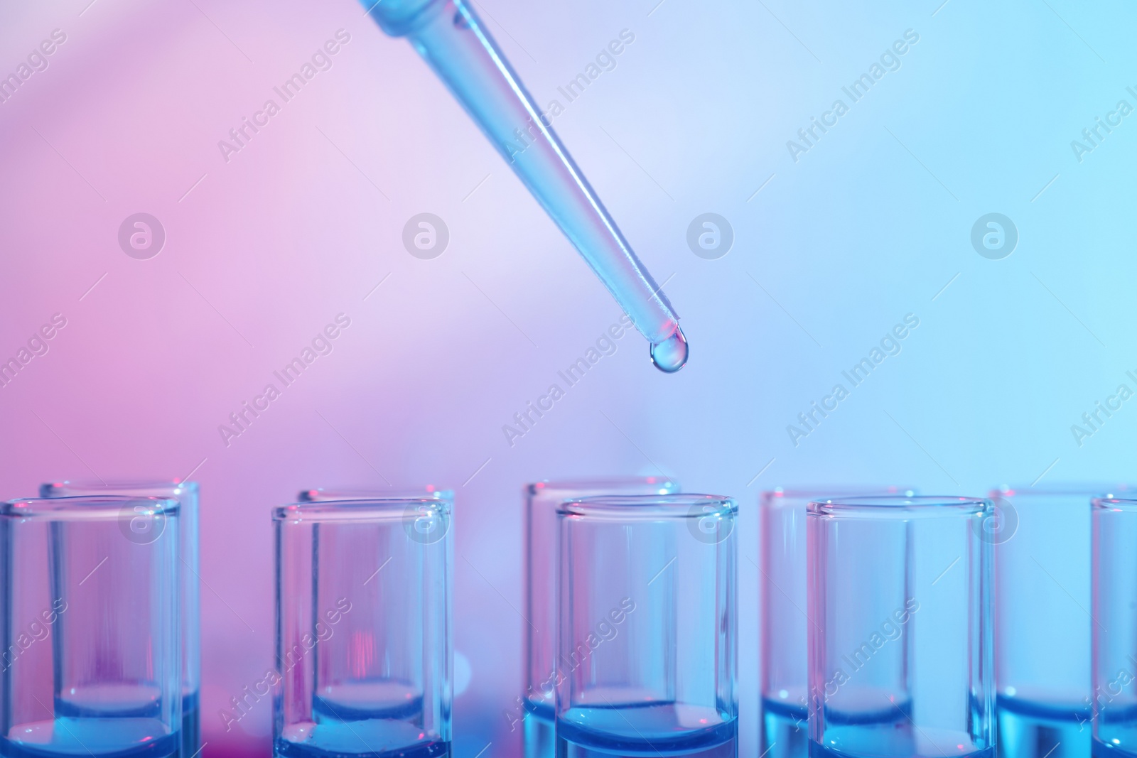 Photo of Dripping reagent into test tube with blue liquid, closeup. Laboratory analysis