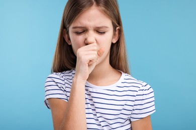 Sick girl coughing on light blue background