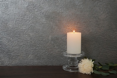 Photo of Decorative candle with flower on table against color background