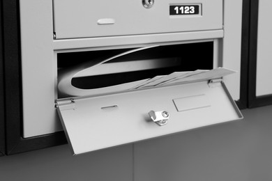 Open grey metal mailbox with envelopes indoors