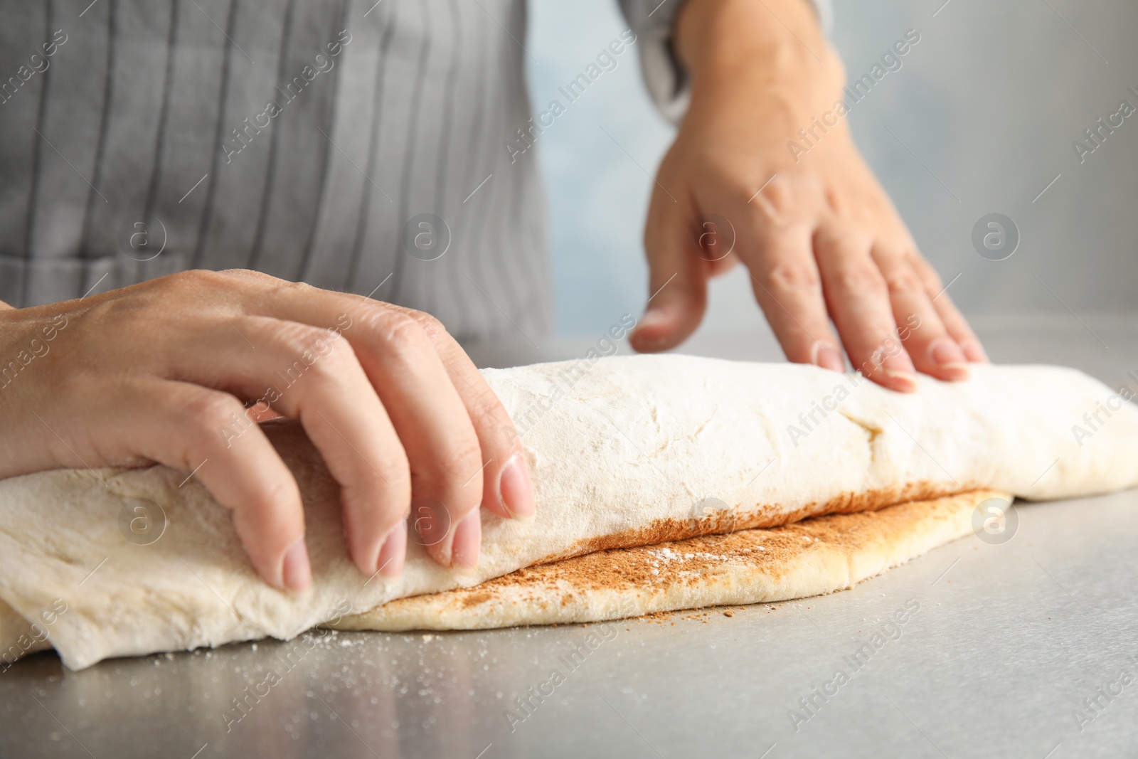 Photo of Woman making cinnamon rolls at table, closeup