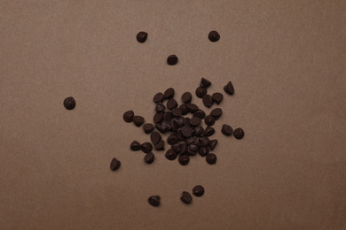 Pile of delicious chocolate chips on brown background, top view