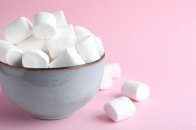 Photo of Delicious puffy marshmallows on pink background, closeup. Space for text