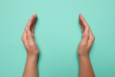 Photo of Woman holding on turquoise background, closeup of hands. Space for text