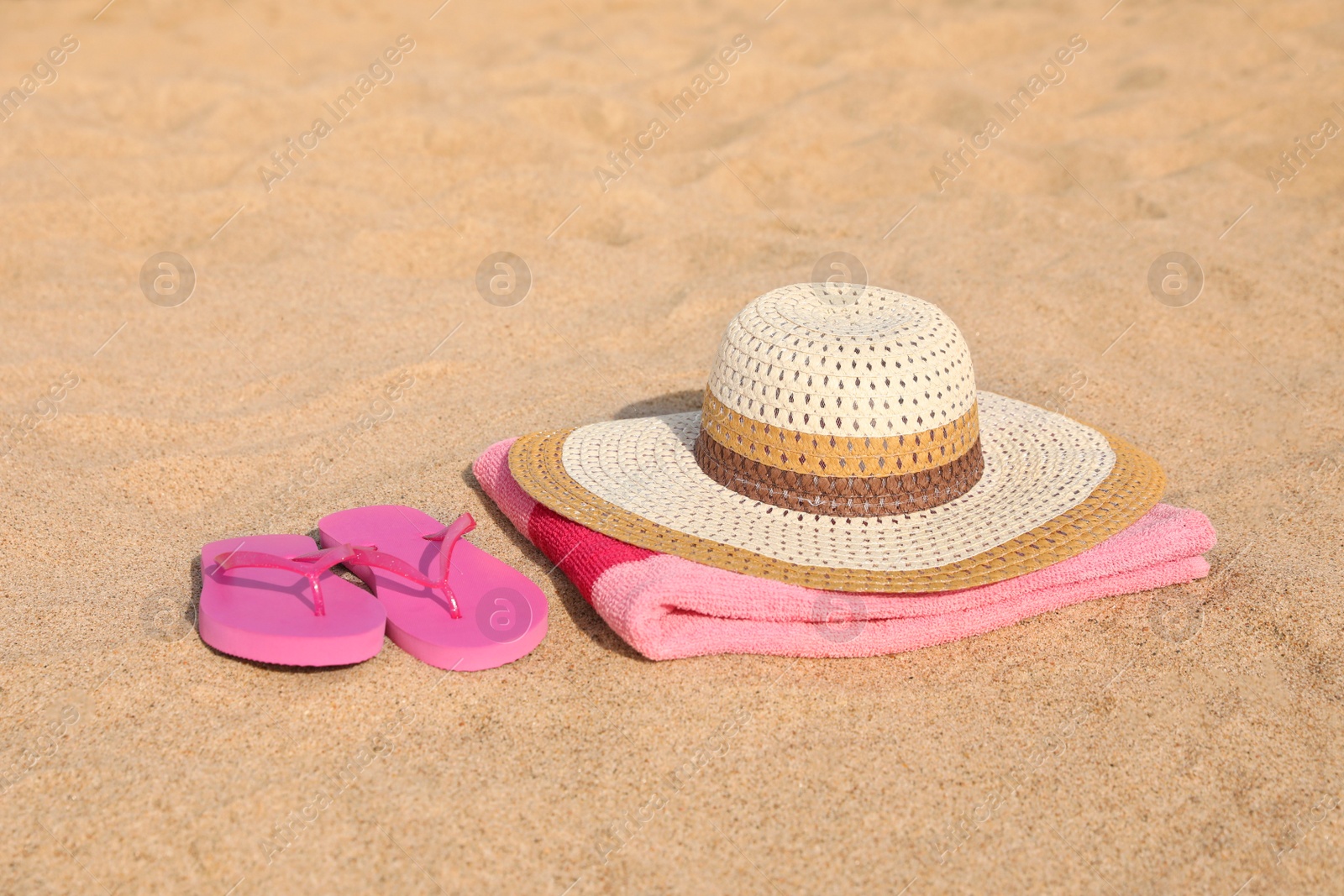 Photo of Beach towel with straw hat and slippers on sand