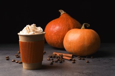 Paper cup with tasty pumpkin spice latte on gray table