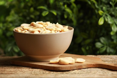 Photo of Fresh peanuts in bowl on wooden table against blurred background, space for text