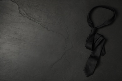 Photo of Top view of stylish elegant necktie on dark background, space for text. Black Friday concept