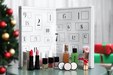 Photo of Christmas advent calendar with perfume and makeup products on table