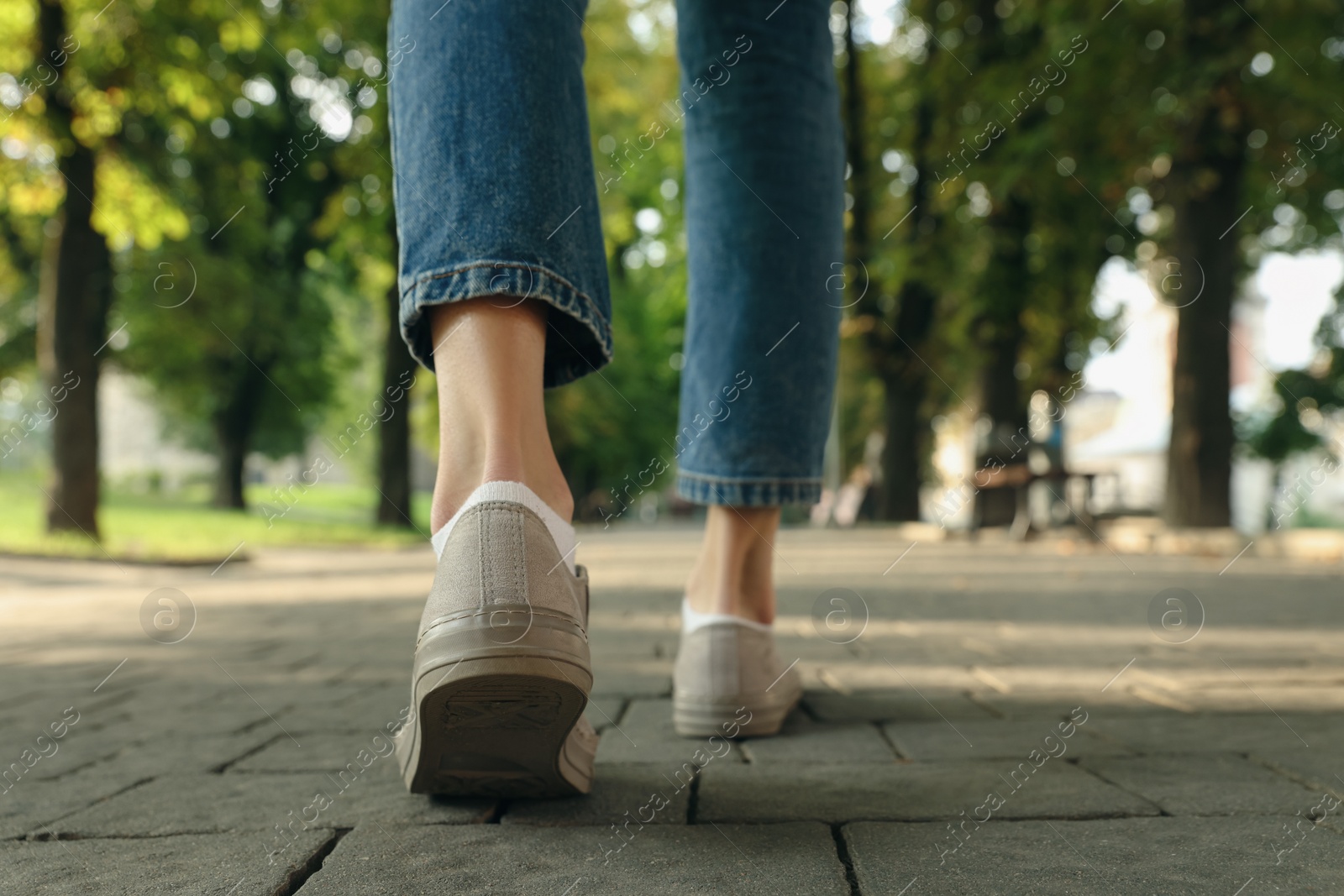 Photo of Woman in stylish sneakers walking on city street, closeup