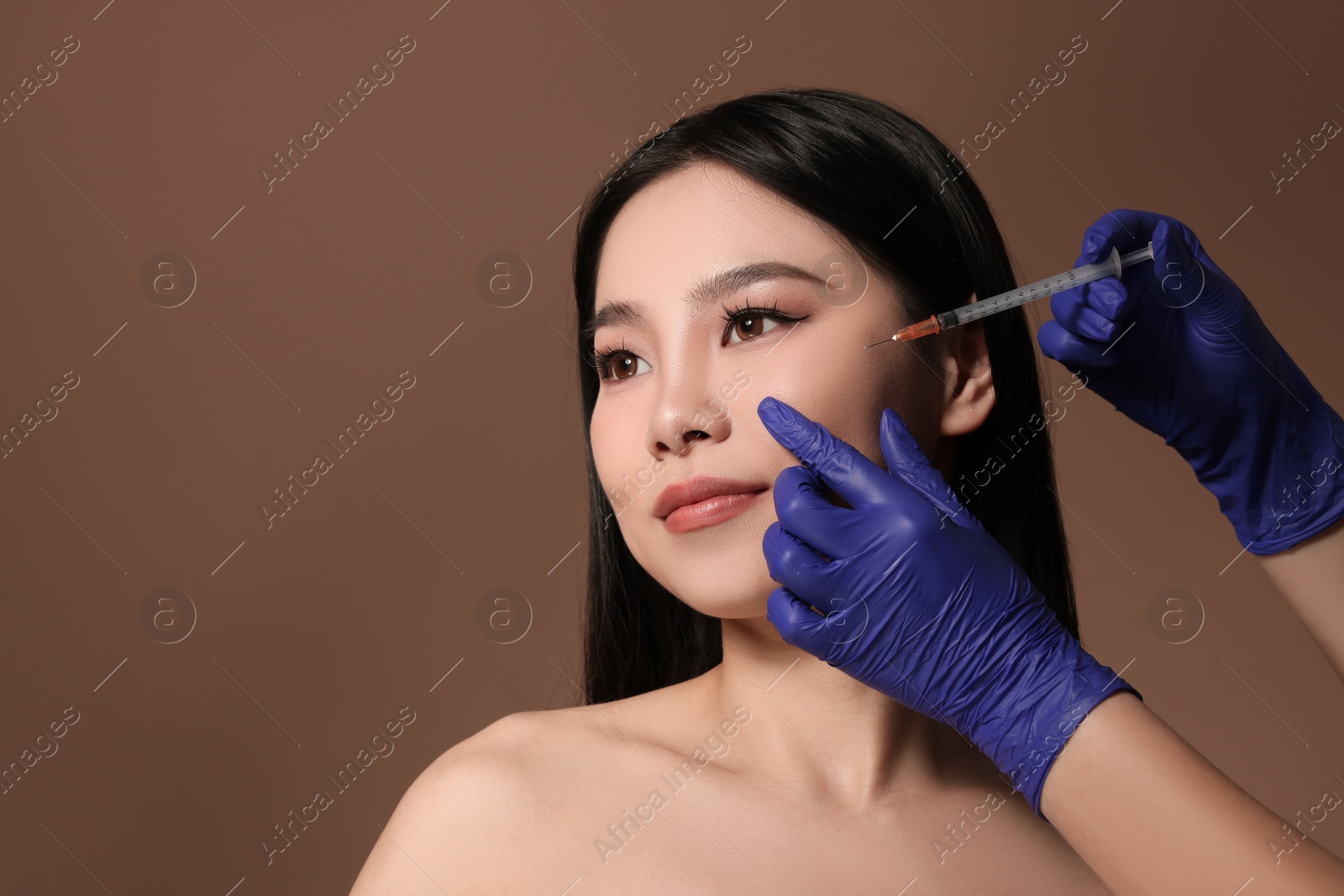 Photo of Woman getting facial injection on brown background