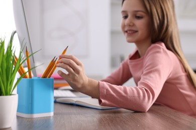 E-learning. Cute girl using computer during online lesson at table indoors, selective focus