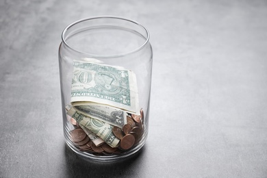 Donation jar with money on grey background. Space for text
