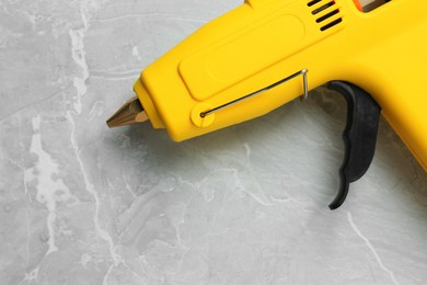 Photo of Yellow glue gun on light grey marble table, above view
