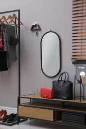 Photo of Modern hallway interior with stylish furniture, mirror and wooden hanger for keys on grey wall