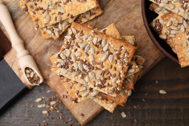 Photo of Cereal crackers with flax, sunflower and sesame seeds on wooden table, top view