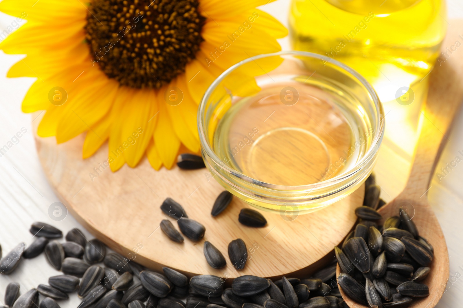 Photo of Sunflower oil and seeds on white table, closeup