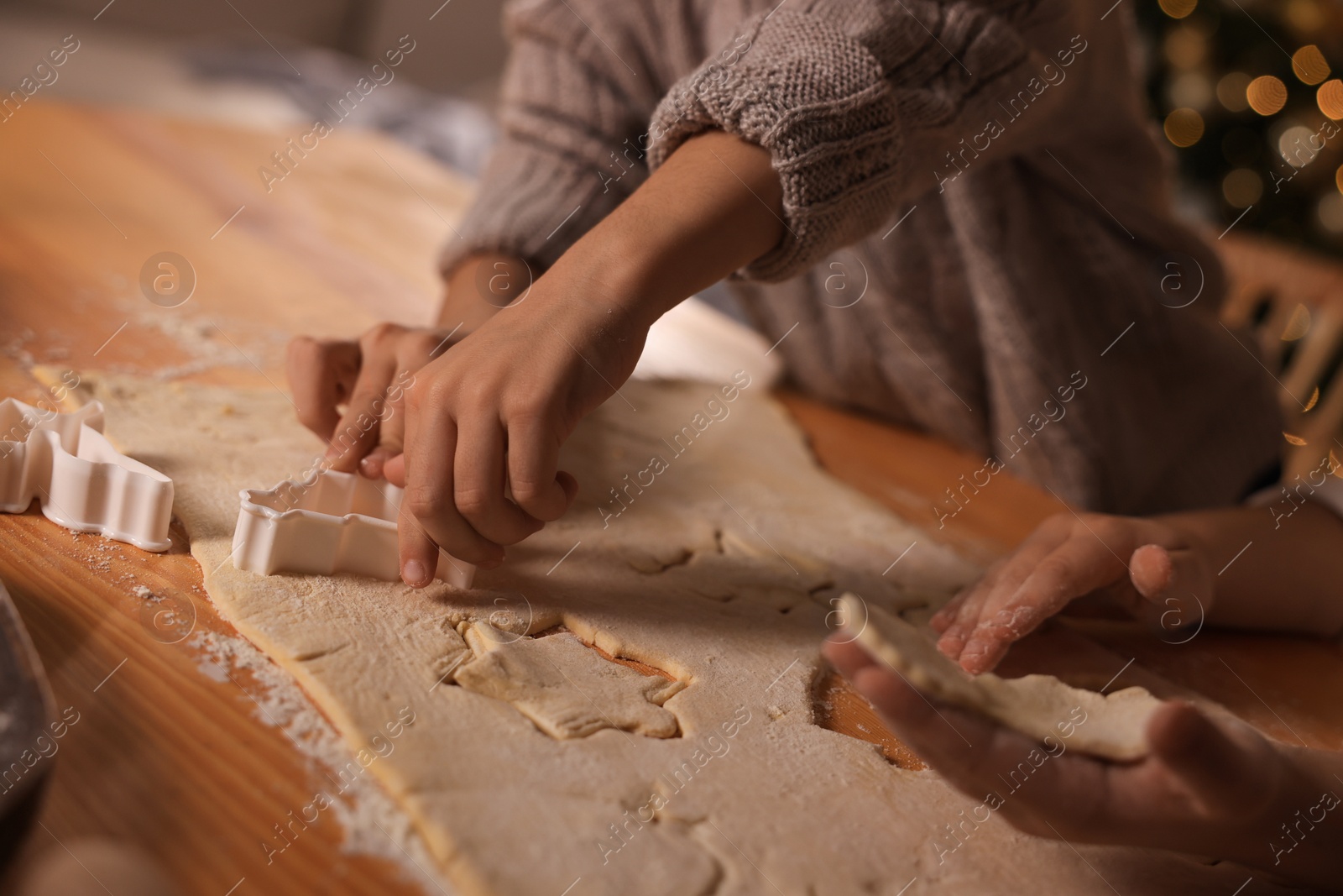 Photo of Little children making Christmas cookies at wooden table, closeup