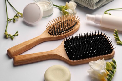 Photo of Wooden hairbrushes, different cosmetic products and beautiful flowers on white background