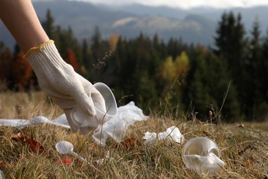 Photo of Woman collecting garbage in nature, closeup of hand with crumpled cup. Space for text
