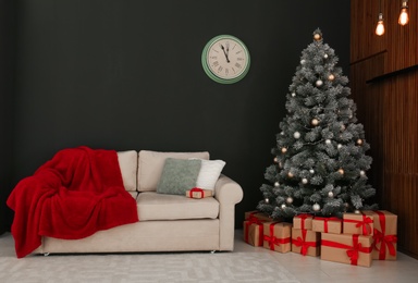 Photo of Stylish Christmas interior with decorated fir tree and comfortable sofa