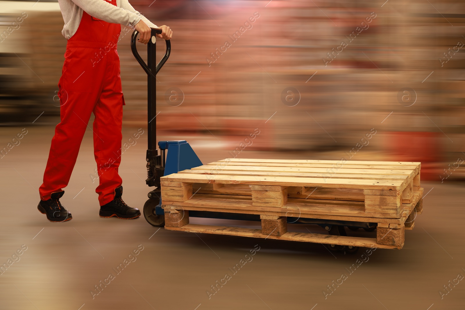 Image of Worker moving wooden pallets with manual forklift in warehouse, closeup