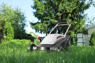 Lawn mower on green grass in garden, low angle view