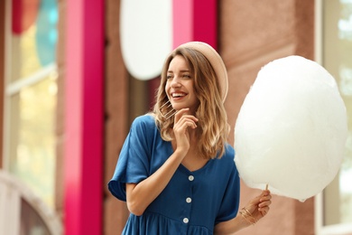 Photo of Happy young woman with cotton candy outdoors