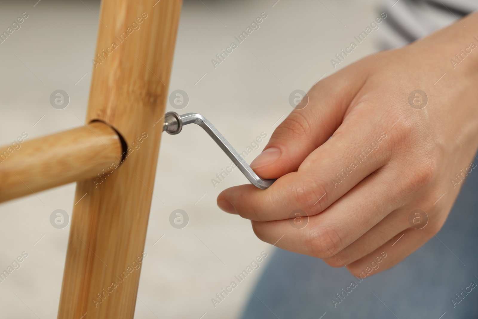 Photo of Woman with hex key assembling furniture indoors, closeup