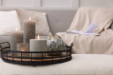 Tray with burning candles on ottoman indoors, space for text