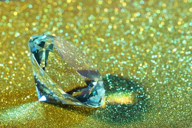 Photo of Beautiful dazzling diamond on glitter background, closeup. Space for text