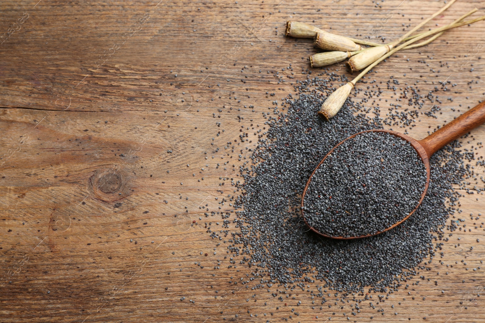 Photo of Dried poppyheads and seeds on wooden table, flat lay. Space for text