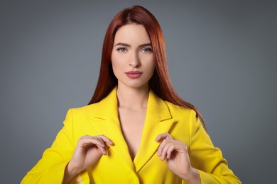 Beautiful woman with red dyed hair on light gray background