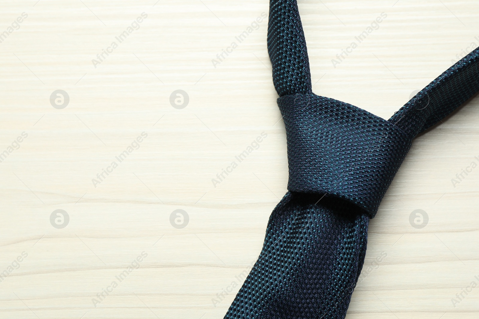 Photo of One blue necktie on white wooden table, top view. Space for text