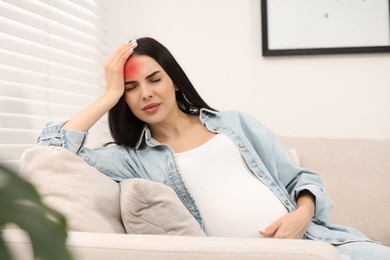 Image of Young pregnant woman suffering from headache at home
