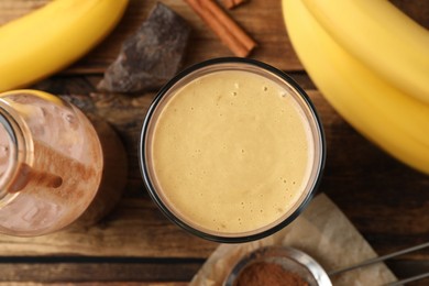 Tasty banana smoothie and ingredients on wooden table, flat lay