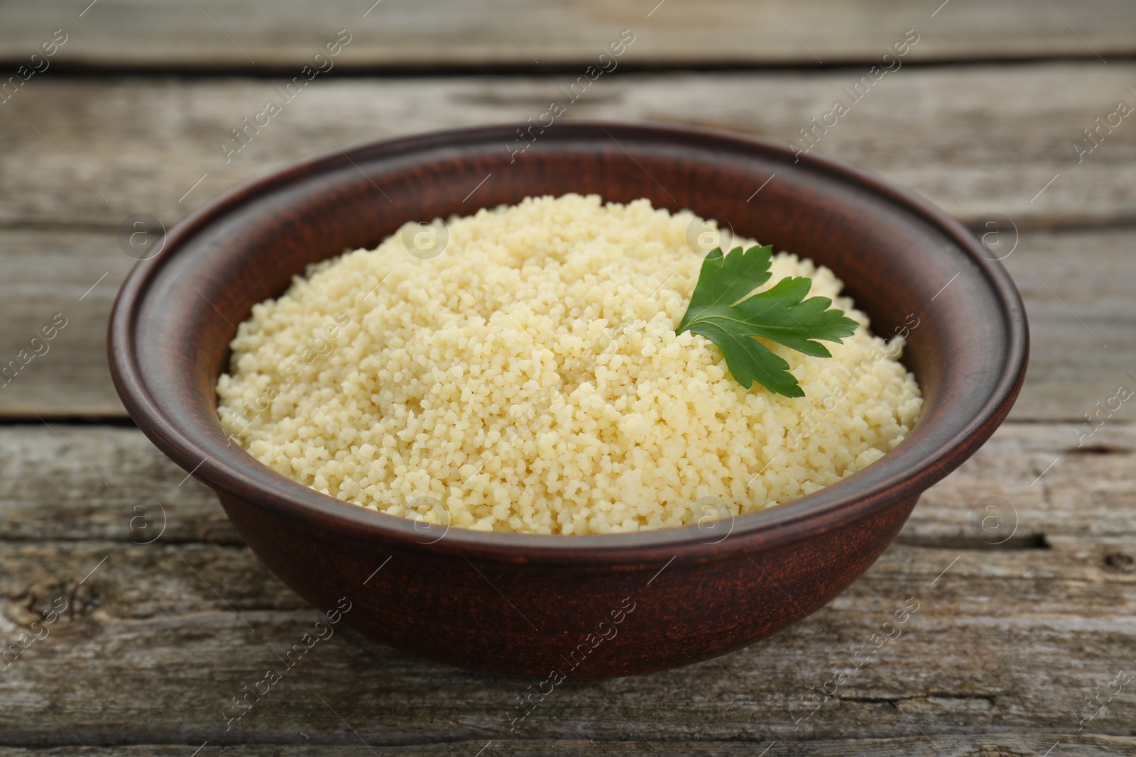 Photo of Tasty couscous with parsley on wooden table, closeup