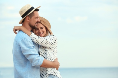 Happy romantic couple spending time together on beach, space for text