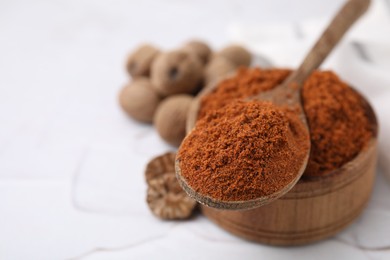 Photo of Bowl and spoon with nutmeg powder on white table, closeup. Space for text