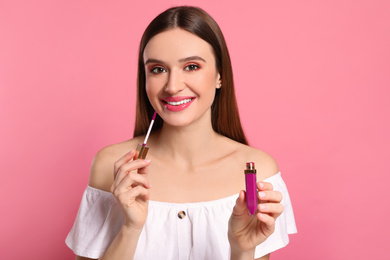 Beauty blogger applying lipgloss on pink background