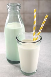 Photo of Glassware with tasty milk on gray light table, closeup