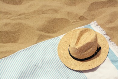 Photo of Beach towel with straw hat on sand. Space for text