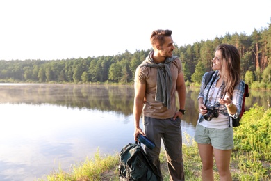 Young couple on shore of beautiful lake. Camping season