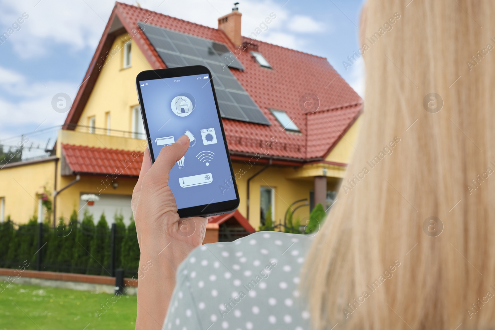 Image of Woman using smart home control system via mobile phone near house outdoors, closeup