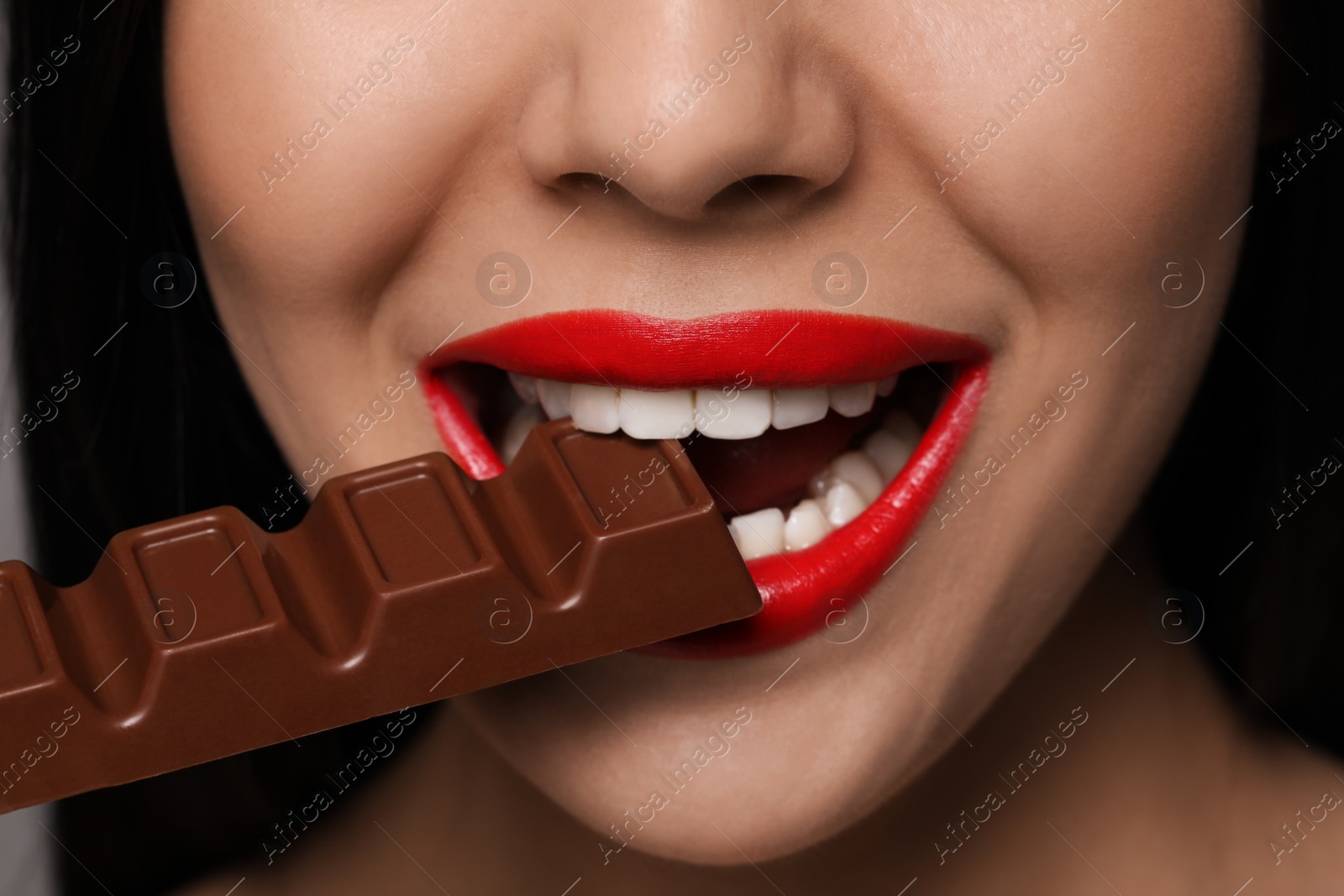 Photo of Young woman with red lips eating chocolate, closeup