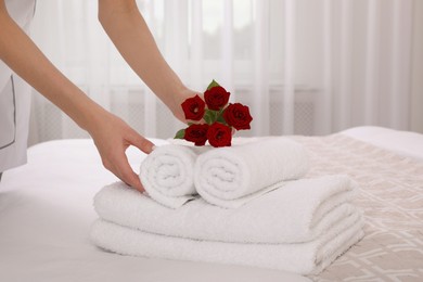 Chambermaid putting flowers with fresh towels in hotel room, closeup
