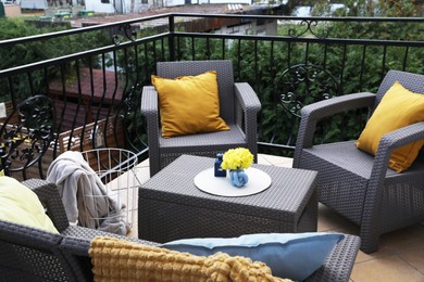 Orange pillows and yellow chrysanthemum flowers on rattan garden furniture outdoors