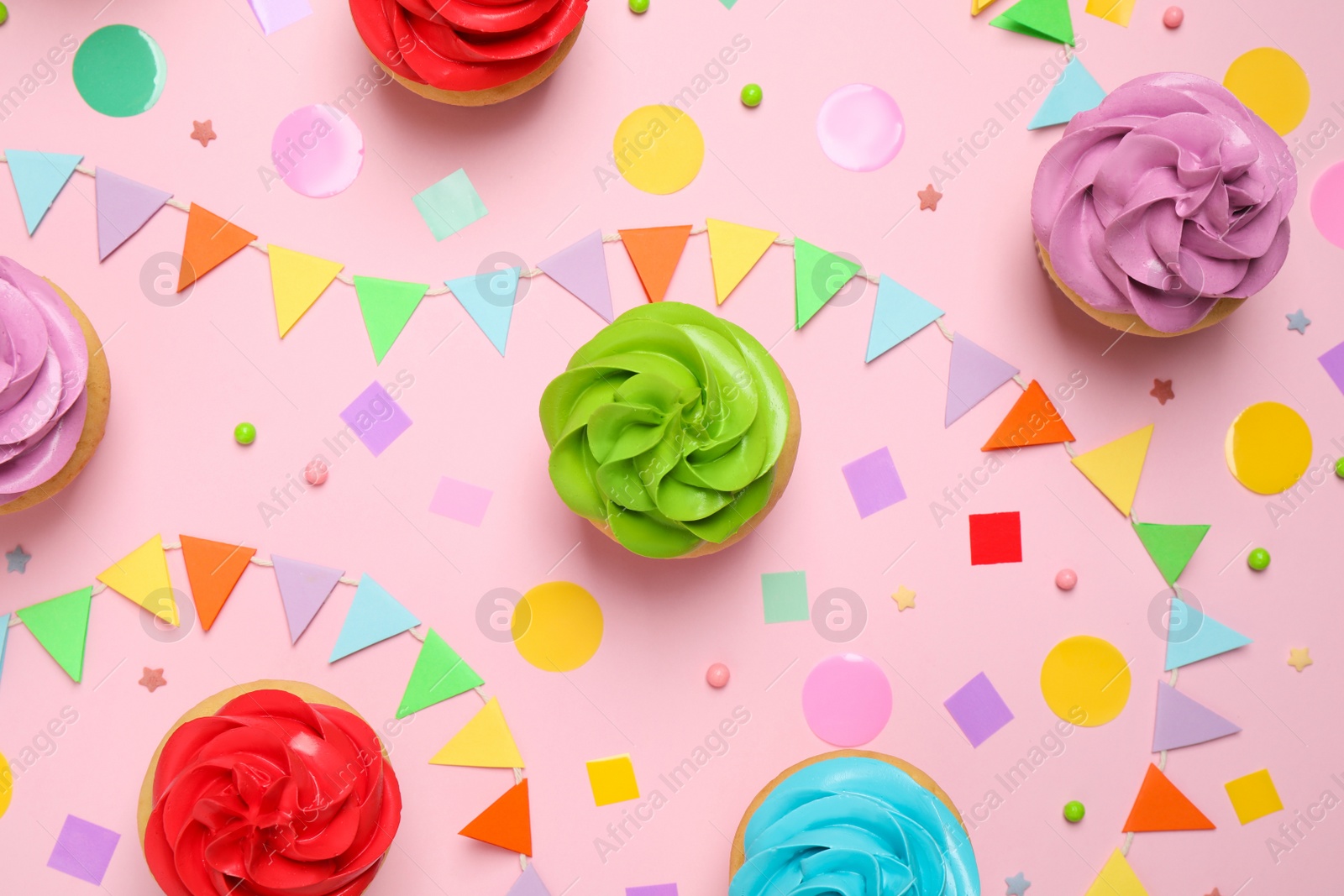 Photo of Colorful birthday cupcakes on light pink background, flat lay