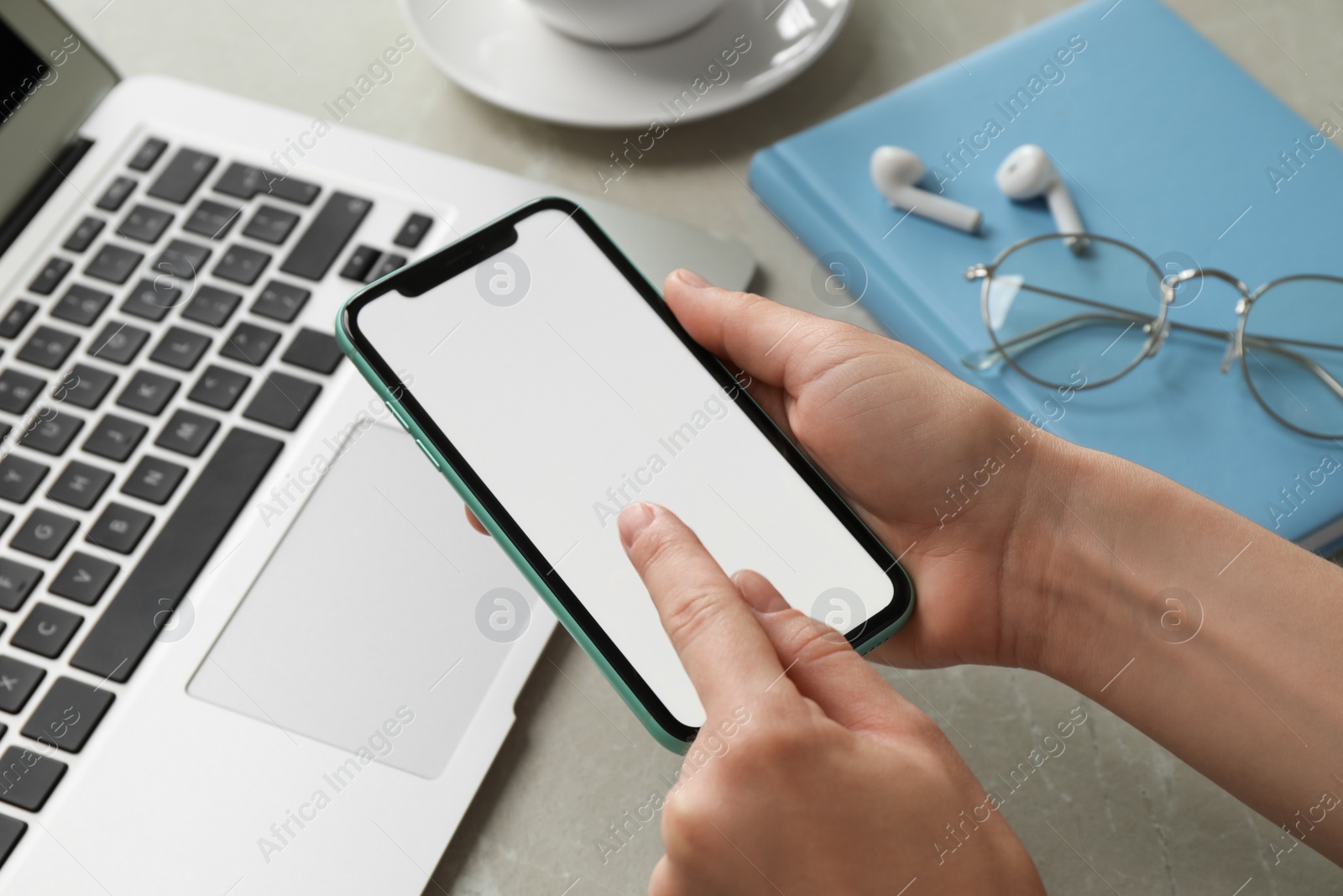 Photo of MYKOLAIV, UKRAINE - JULY 8, 2020: Woman using Iphone 11 Pro Max with blank screen at workplace, closeup